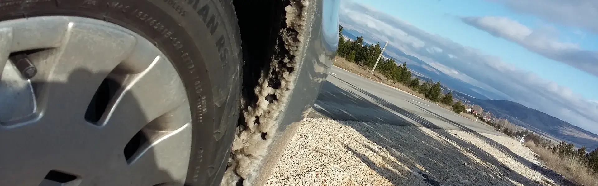 Auto Vorderrad auf einer Strasse mit einer Stadt im Hintergrund